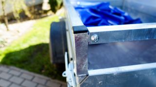A small galvanised trailer with a tarp for covering green waste.